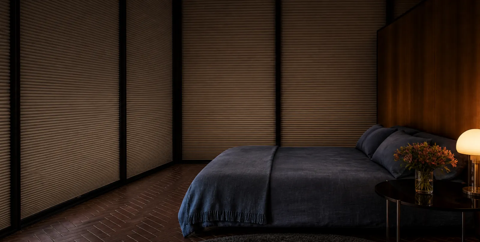 Dark blackout honeycomb shades lowered in a warm bedroom