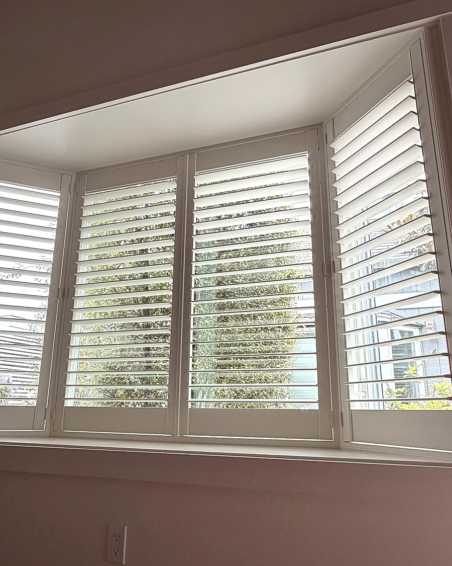 White plantation shutters installed on an angled Ventura County bay window