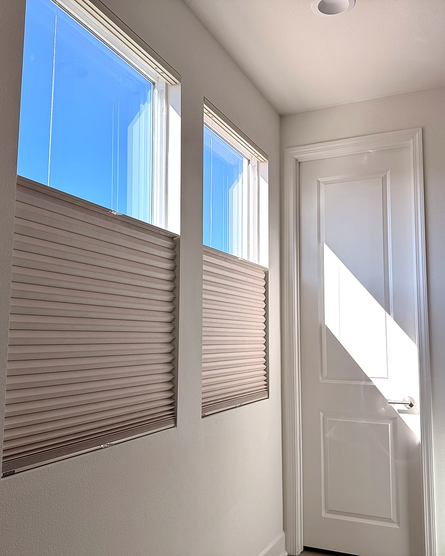 Cellular shades installed on two bedroom windows beside a door